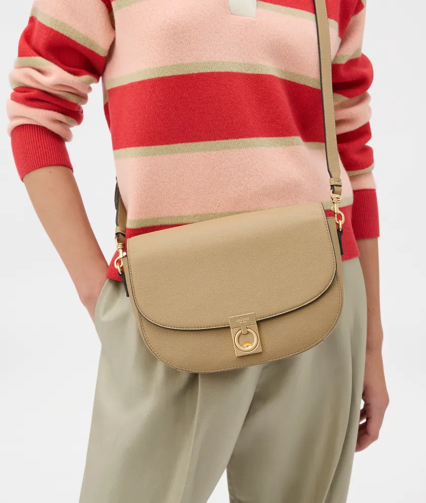 Person wearing striped sweater holding a beige crossbody bag.