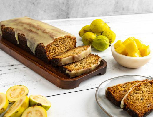 Banana Guava and Pineapple bread loaf with slices, surrounded by fruits and a bowl of pineapple.