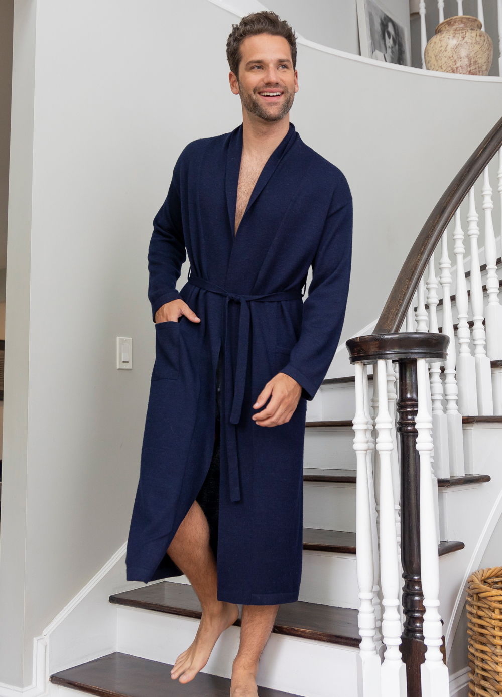 Man in a navy robe standing on stairs, smiling and relaxed.
