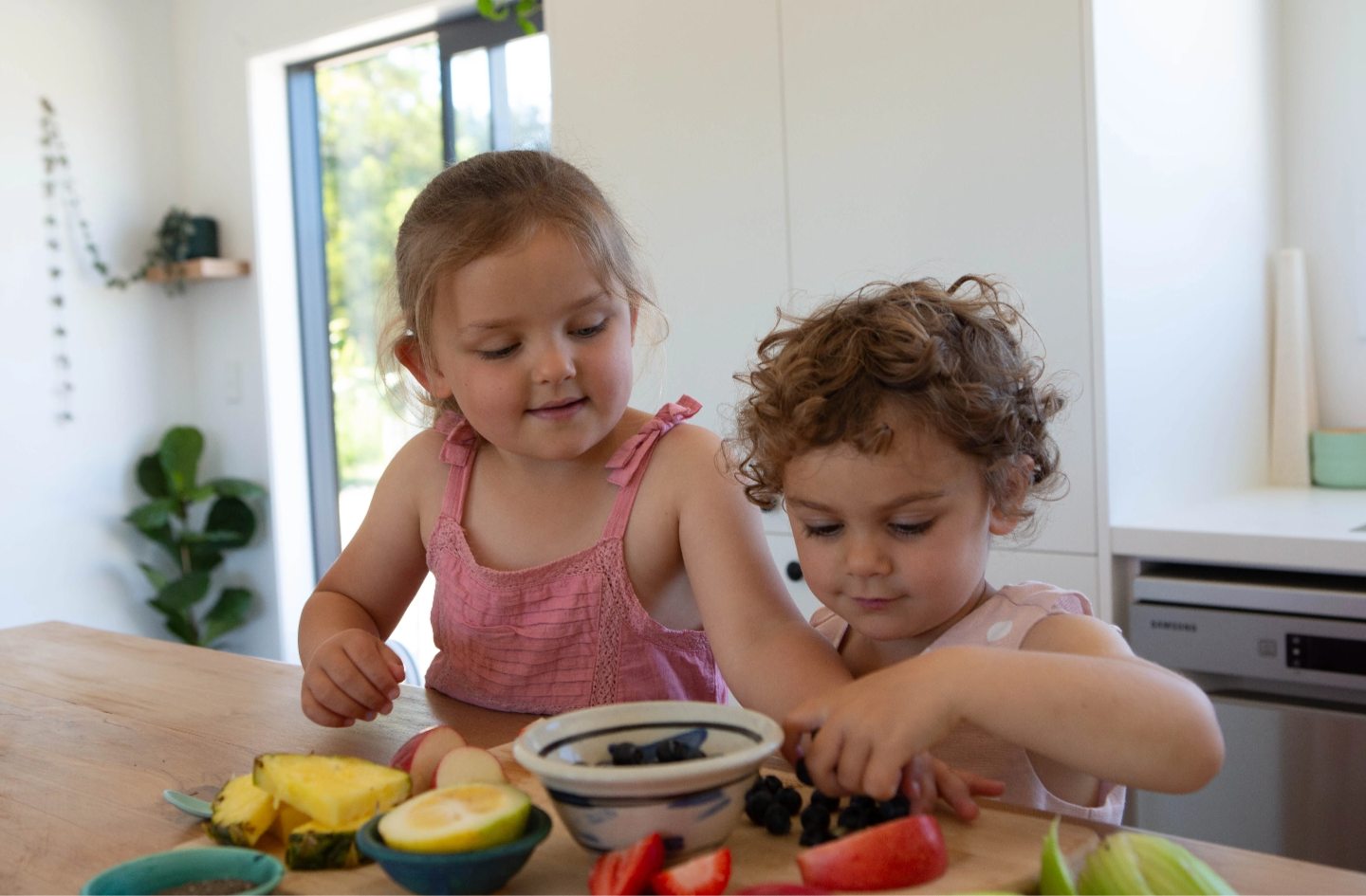 two young girls making a fruit salad