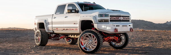 Front three-quarter view of Juan's white lifted 2018 Chevrolet Silverado 2500HD with red suspension and large chrome wheels, Conductor's Special 244K install photo 1