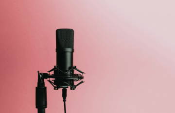 Microphone on a stand against a gradient pink background.