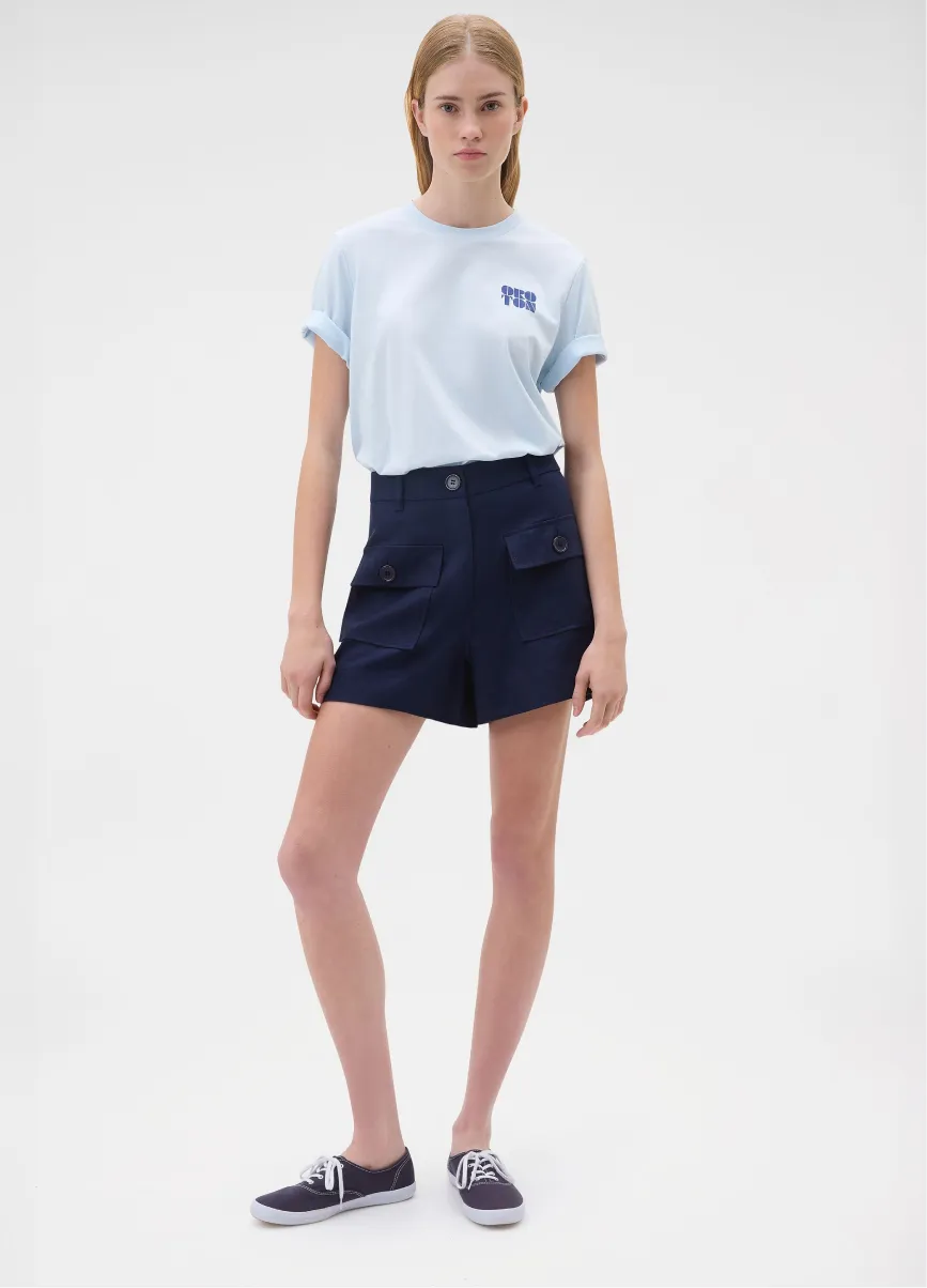 A young woman wearing a light blue t-shirt and navy shorts.