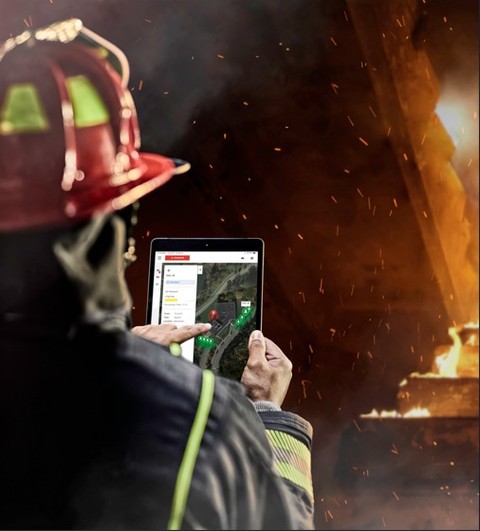 Firefighter using a tablet to monitor a fire scene.
