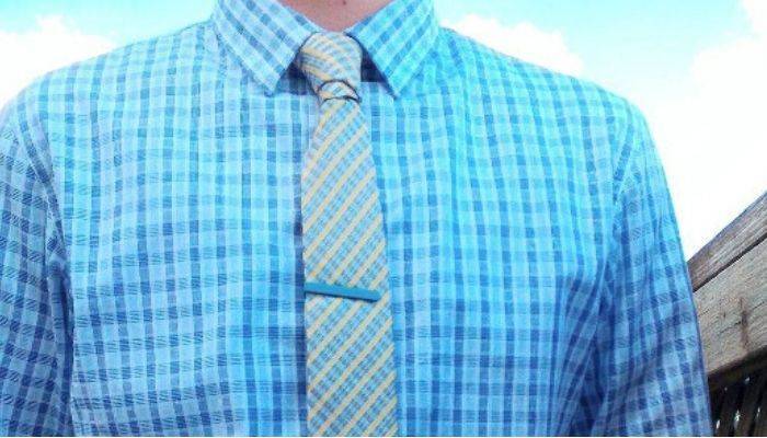 Man wearing a plaid shirt, tie and colored tie bar