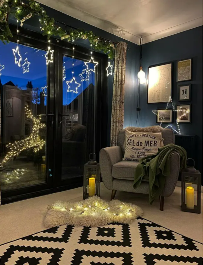 A cosy living room setting with star lights and a reindeer in the garden.