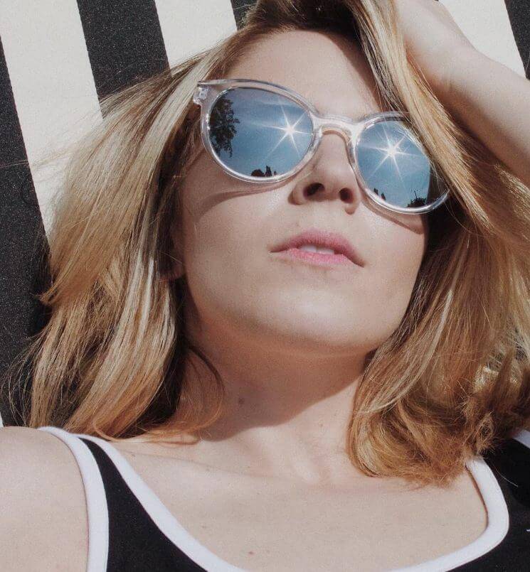 Femme portant des lunettes de soleil et regardant le soleil
