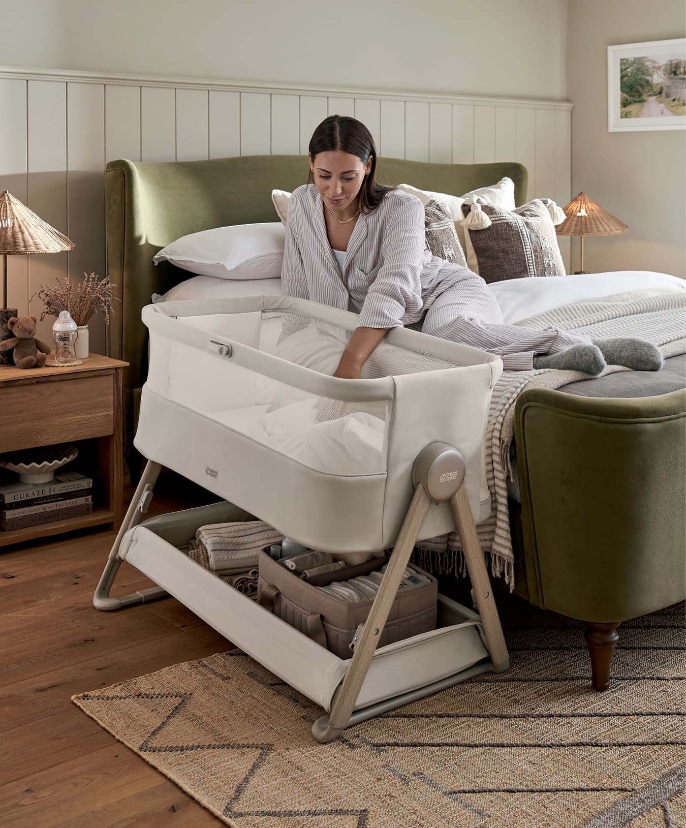 Woman interacting with a baby bassinet next to a bed in a cozy room.