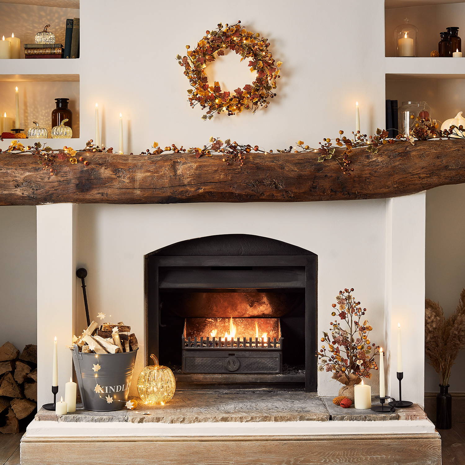 An autumn fireplace setting with a wreath and garland and pumpkin decorations around the hearth.