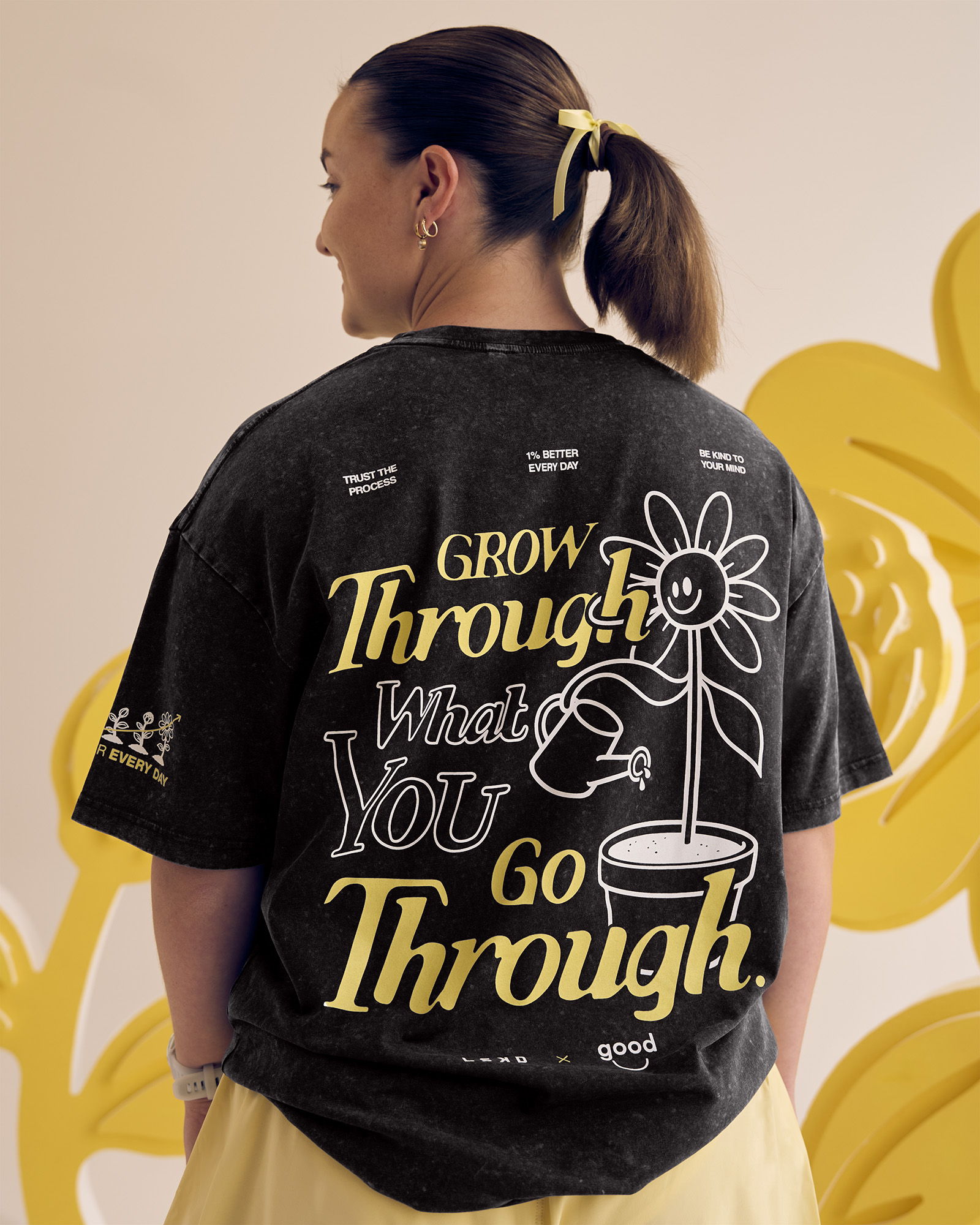 Person wearing a black shirt with a motivational quote and flower graphic.