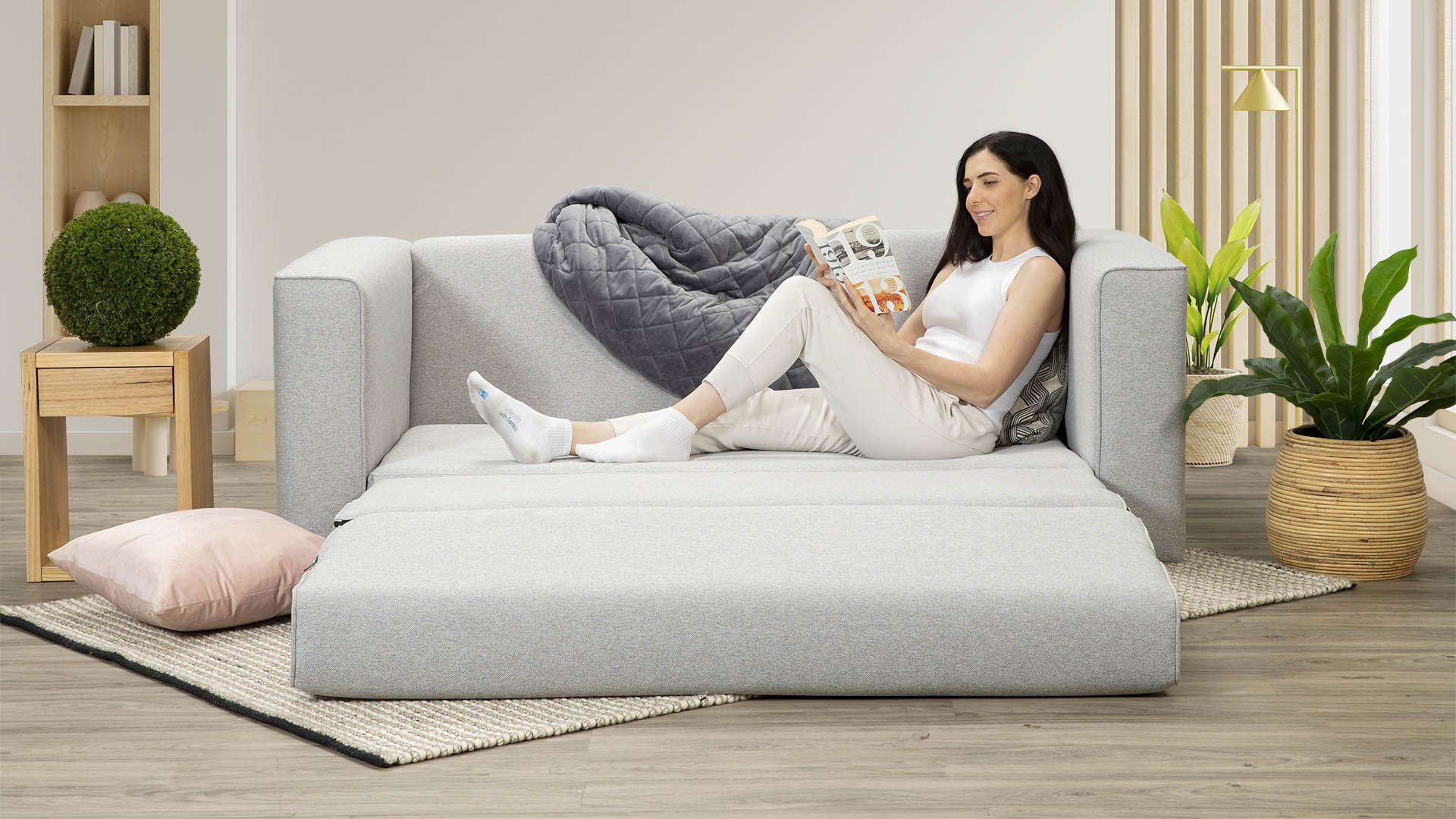 A Zeek model lying on a brand new silver Sofa Bed.