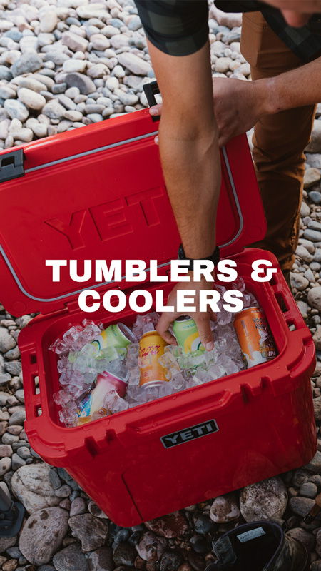 Person reaching into a red cooler filled with ice and beverages.