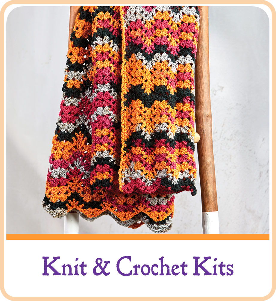 Colorful knitted and crocheted scarf displayed on a wooden hanger.