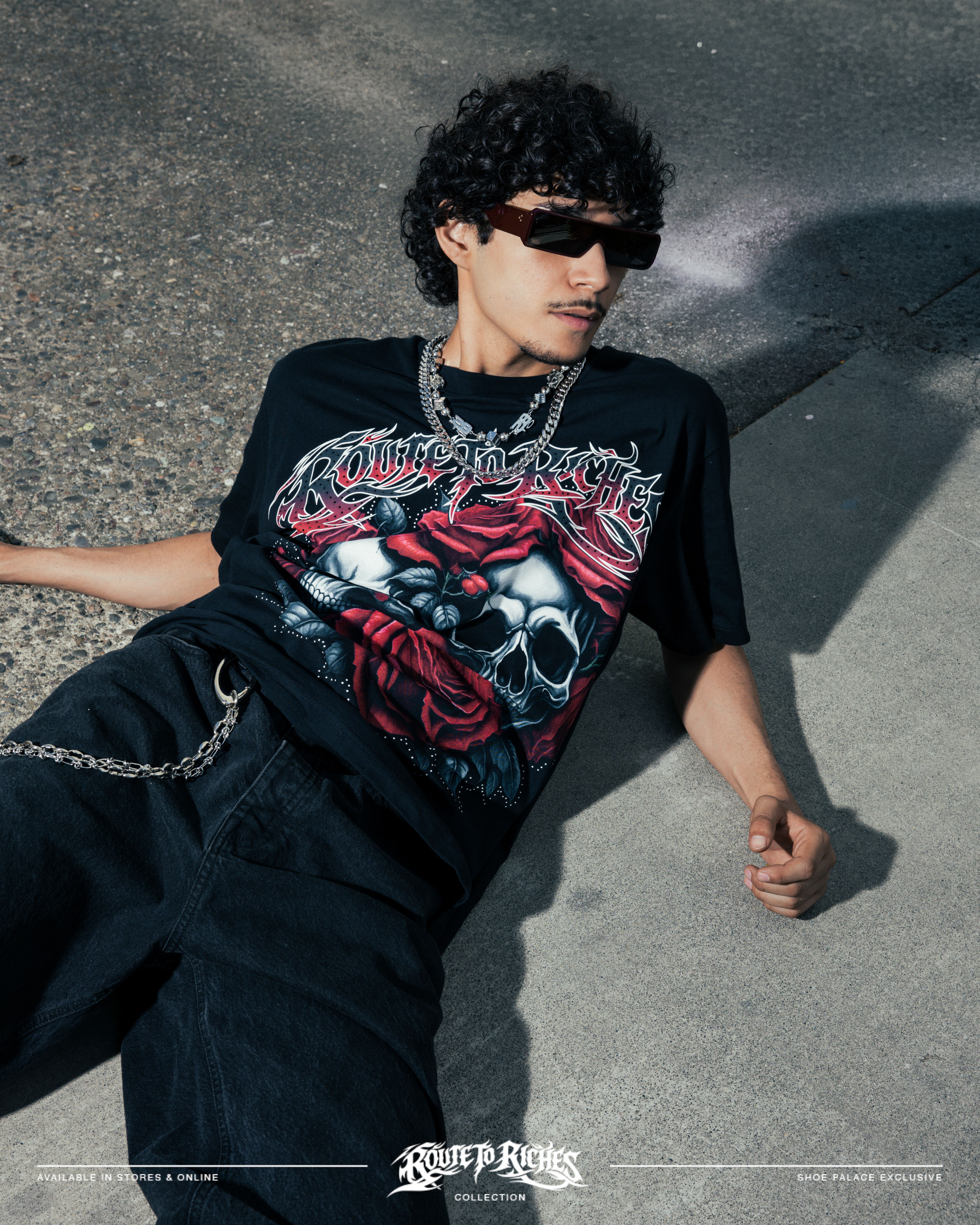 Person lying on the ground wearing a graphic t-shirt and sunglasses.