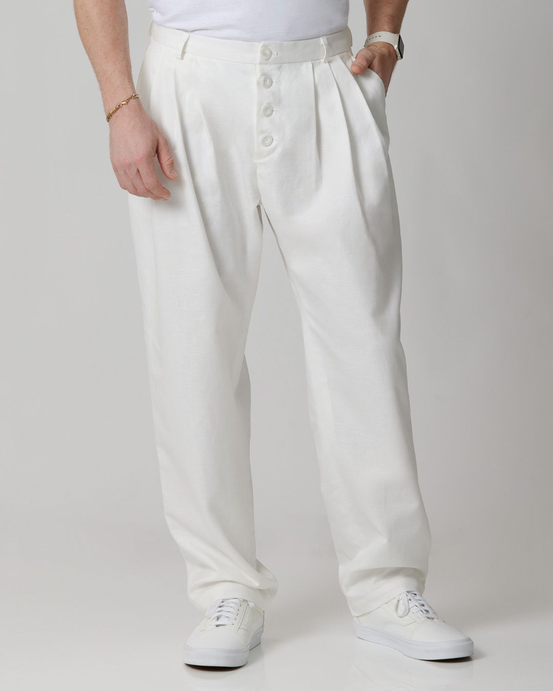 Person wearing white pants and sneakers, standing against a neutral background.