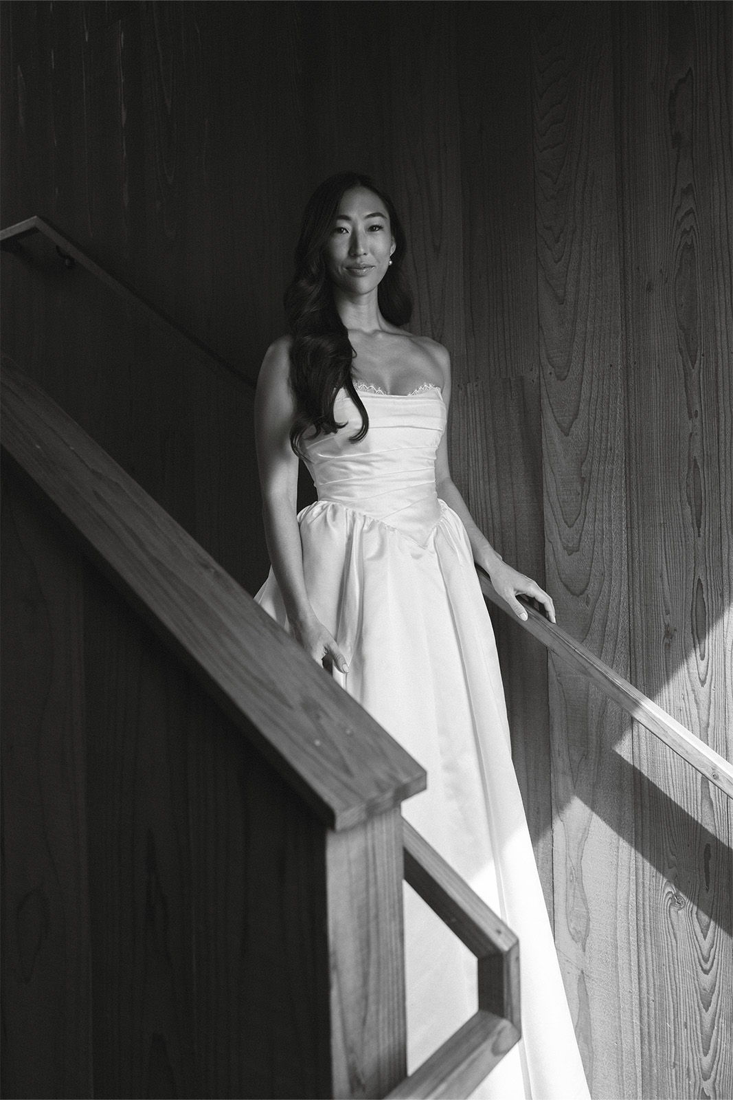 Woman in a white dress standing on a staircase in black and white.