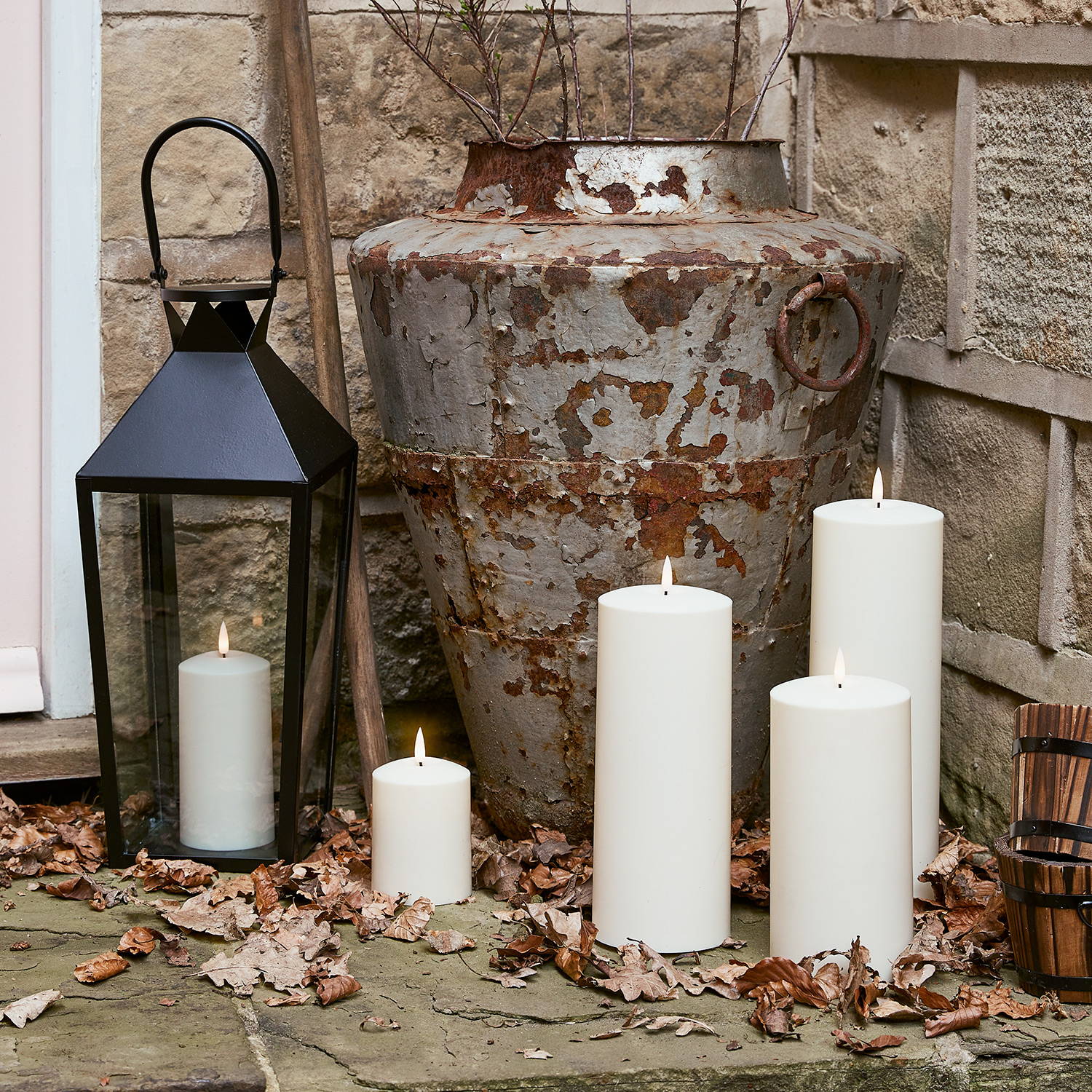 A close up of an autumn entrance with LED outdoor candles and a black candle lantern.