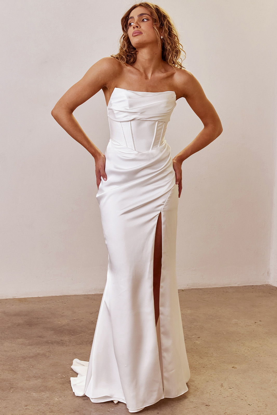 Model in a strapless wedding dress with a thigh-high slit.