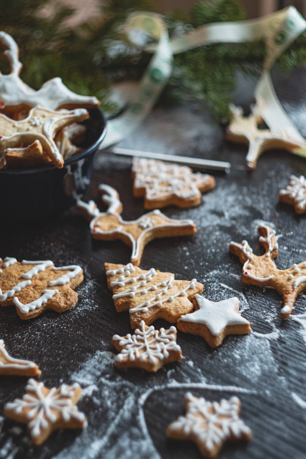 Iced and decorated gingerbread cookies on a counter dusted with flour.