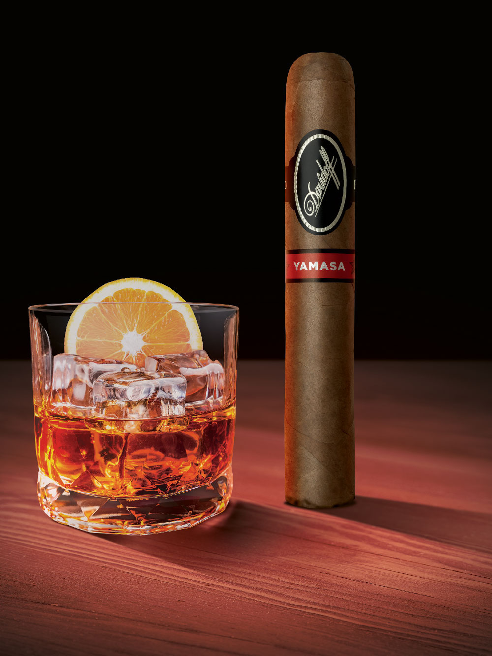 Eine Davidoff Yamasá-Zigarre, die aufrecht neben einem Glas mit Whisky steht.