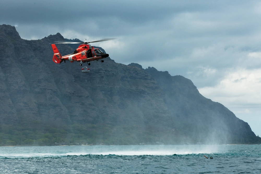 A Coast Guard Eurocopter HH-65 Dolphin helicopter moves over Kaneohe Bay toward simulated casualty Cpl. Brad Rosati, a navigation aids technician with Air Traffic Control maintenance, Marine Corps Air Station Kaneohe Bay, during a joint-service aircraft mishap drill over Kaneohe Bay, Hawaii, Oct. 18, 2010. Built on the premise of a simulated CH-53D Sea Stallion helicopter crash over water, the drill allowed the joint-service team to work through standard operating procedures for air and waterborne rescue operations.