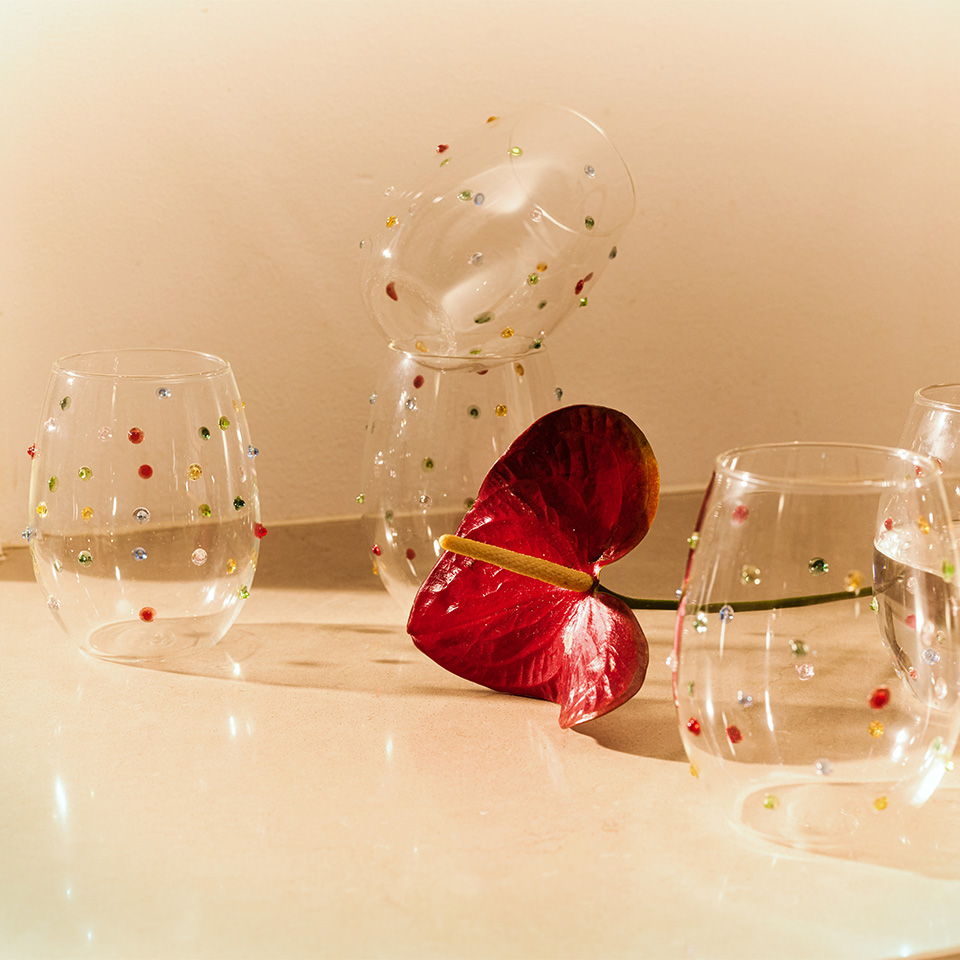 Transparent glasses and a red flower on a light background.