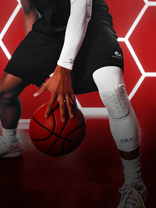 Person dribbling a basketball, wearing a black outfit and white sleeve.