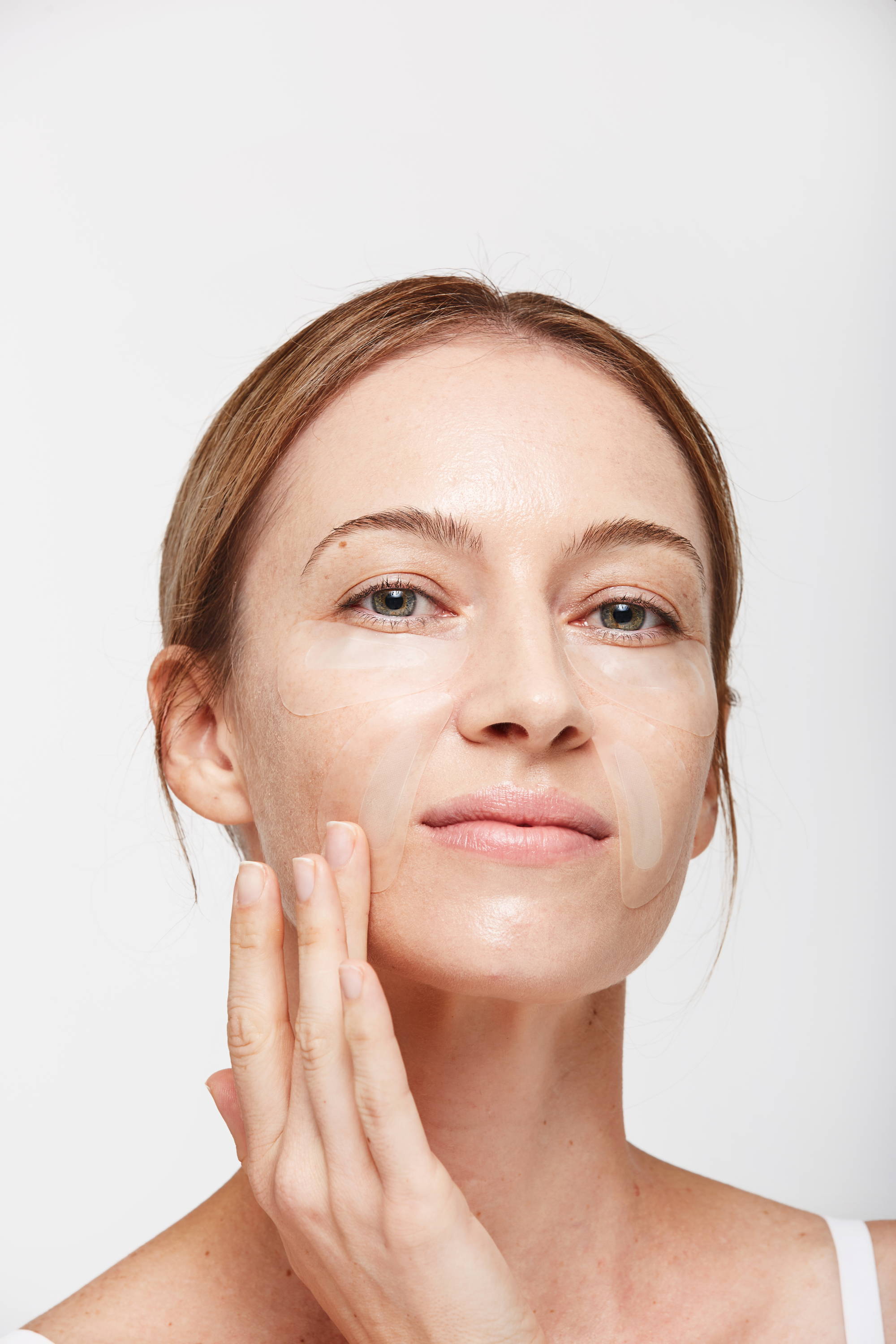 Woman in her 40s wearing Hyaluronic microneedling patches for under eye area and corws feet