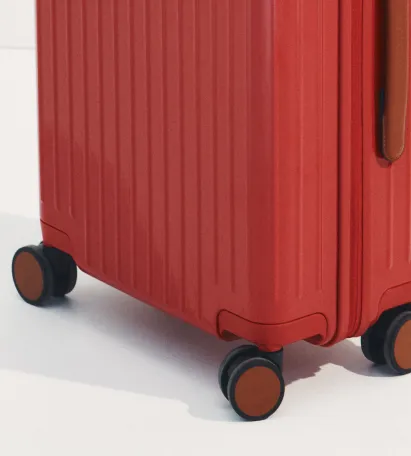 Red suitcase with wheels and textured surface.