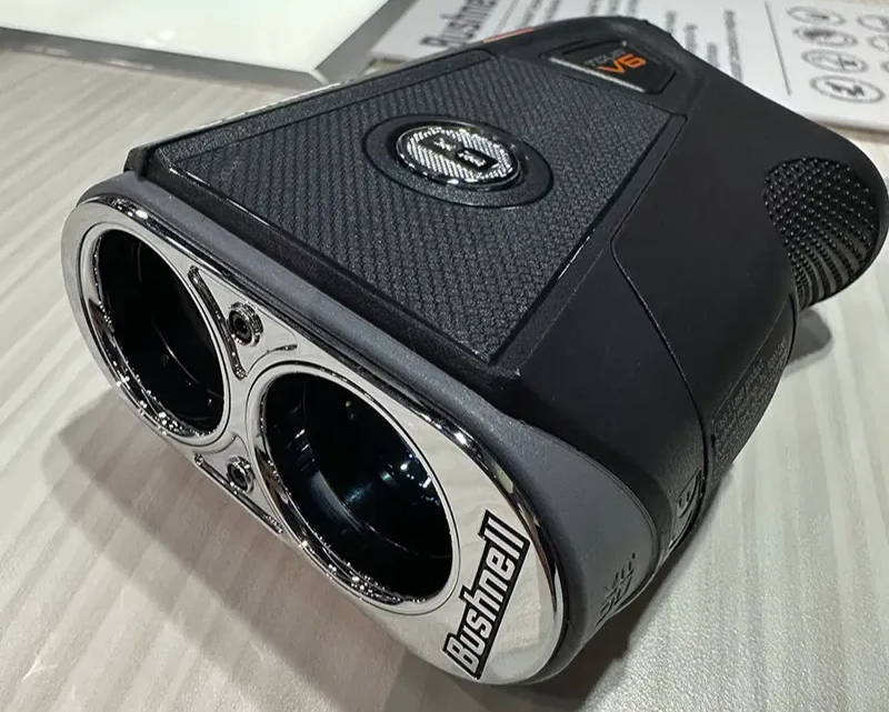 The Bushnell Tour V6 golf laser rangefinder laying on it's side with a view of the front lenses