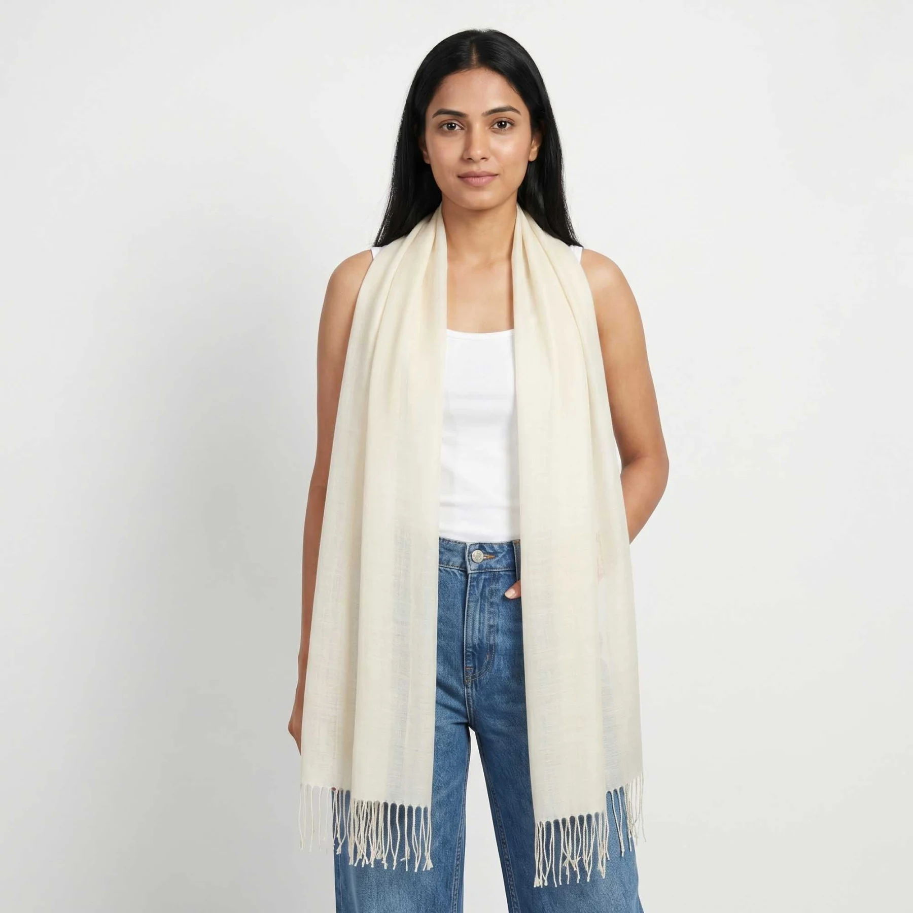 A woman wearing a white scarf and casual outfit, standing against a plain background.