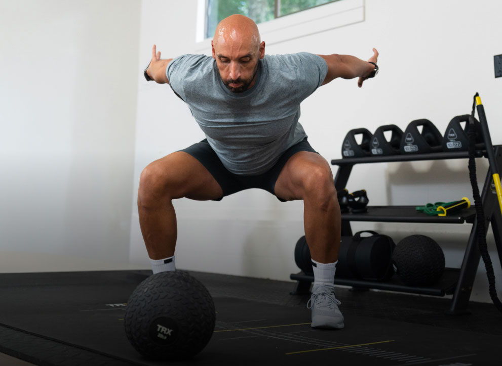 Man exercising with a medicine ball in a gym setting.