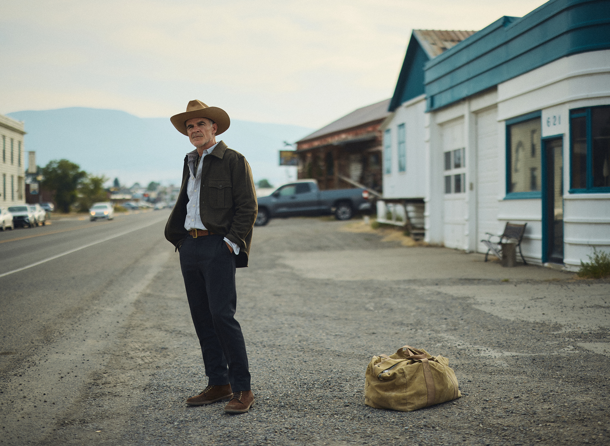 Michael Kelly hitchhiking through Livingston, Montana wearing the Meade Wool Glen Plaid Overshirt in Olive Drab and the Rivay X Alden Bedford Boot in Rough out Suede