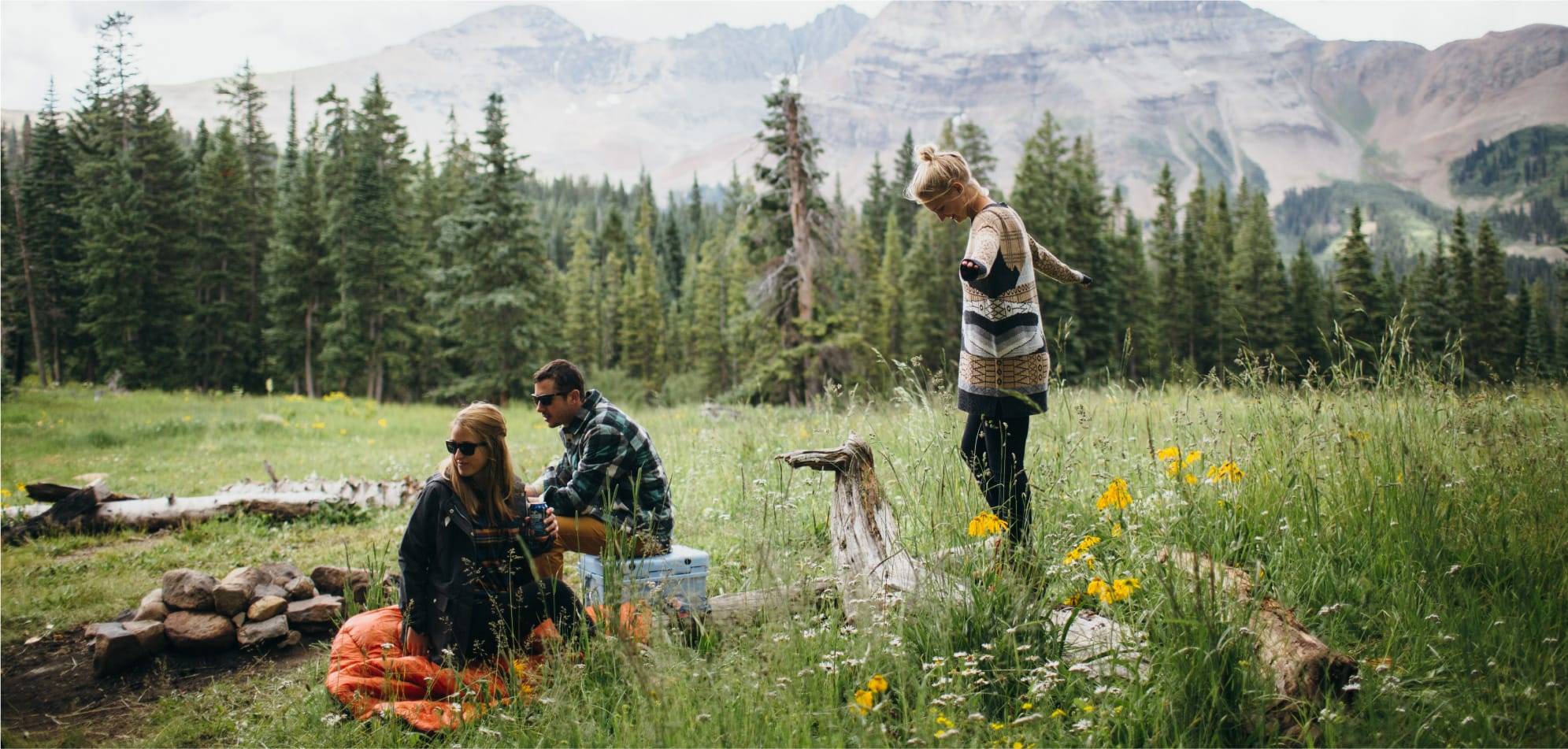 Three people in the forest having a picnic with a Rumpl blanket