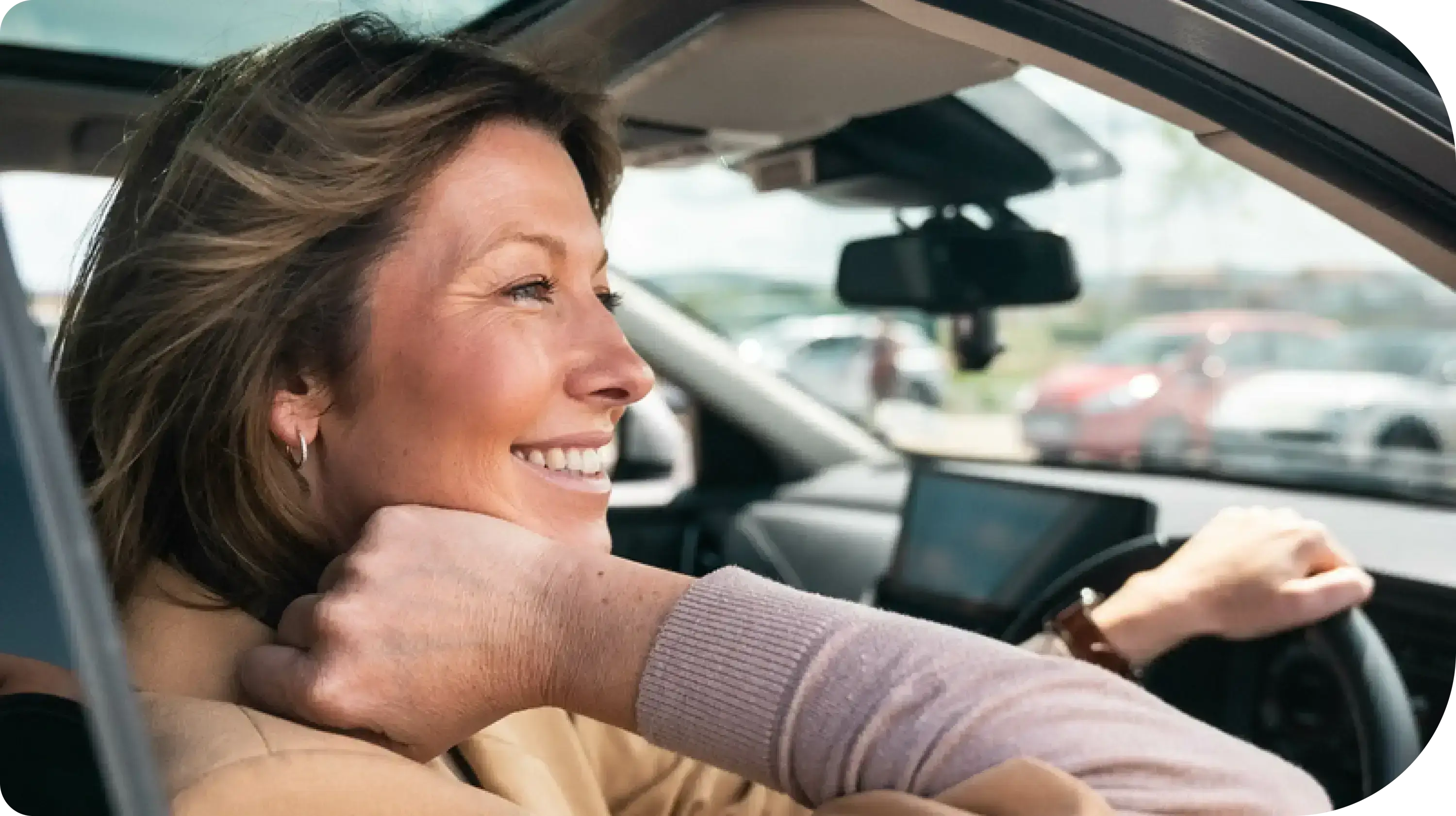 Smiling woman driving a car, looking out the window.