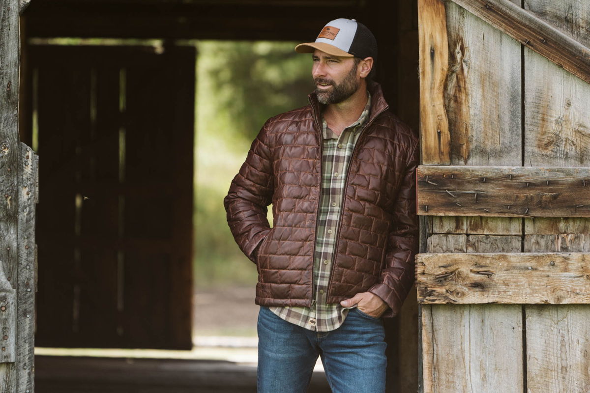 Man in a Buffalo Jackson brown quilted leather jacket and plaid flannel shirt in a barn doorway