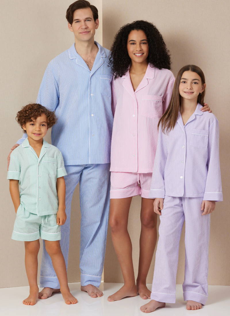 Family in matching pajamas, standing together against a neutral background.