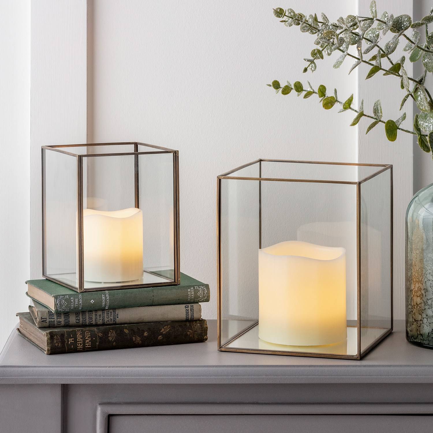 2 Glass jars with LED candles on a table with some books.