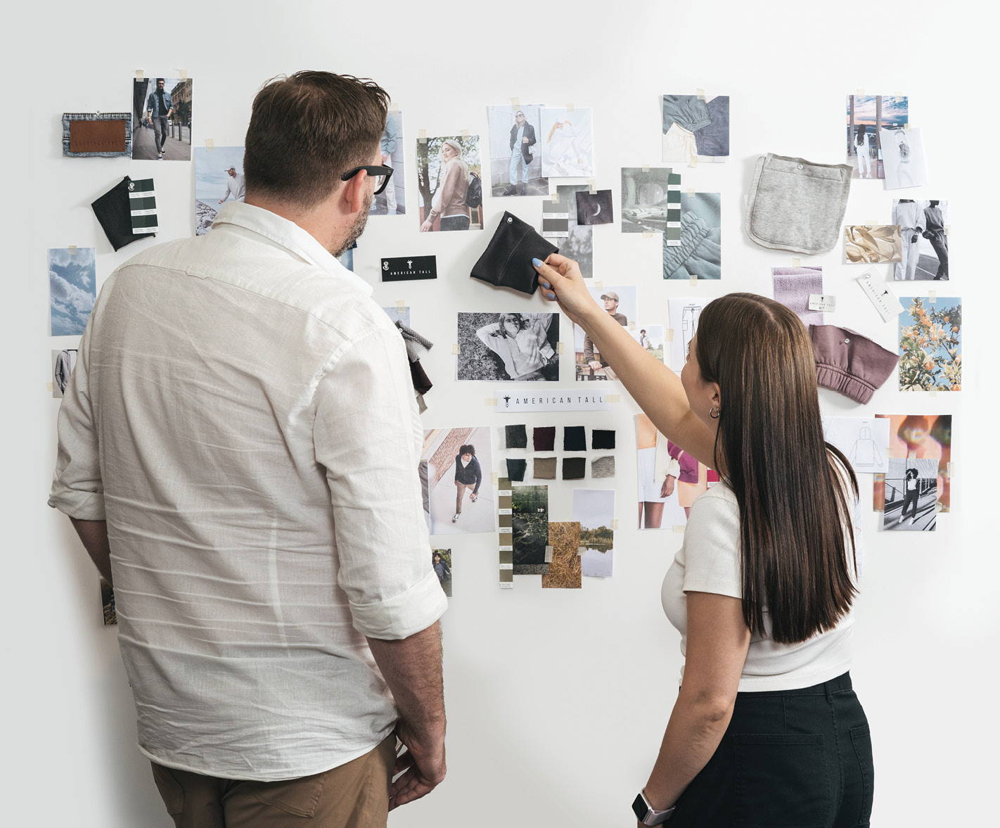 Two employees looking at fabric swatches and photos on the wall