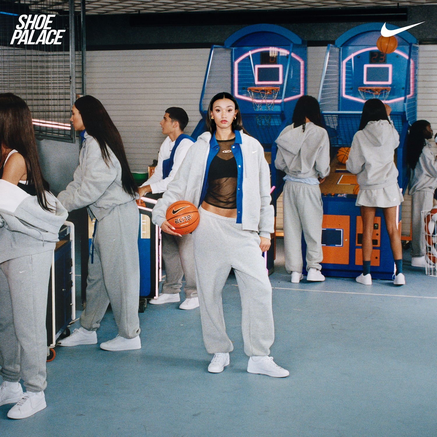 Group of people playing basketball in casual attire at an indoor court.