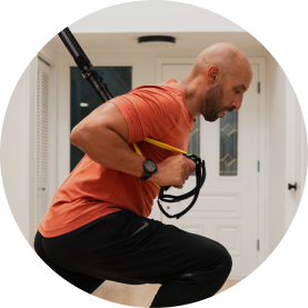 Man exercising with suspension trainer in a home setting.