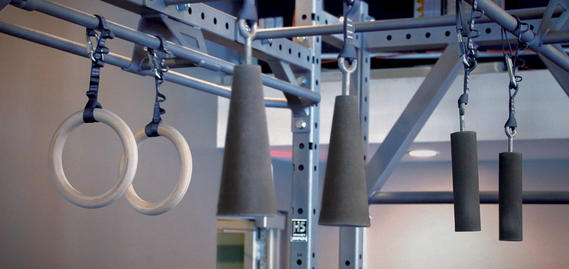 Hanging accessories suspended from Hammer Strength rack: Olympic rings, cones, pipe set