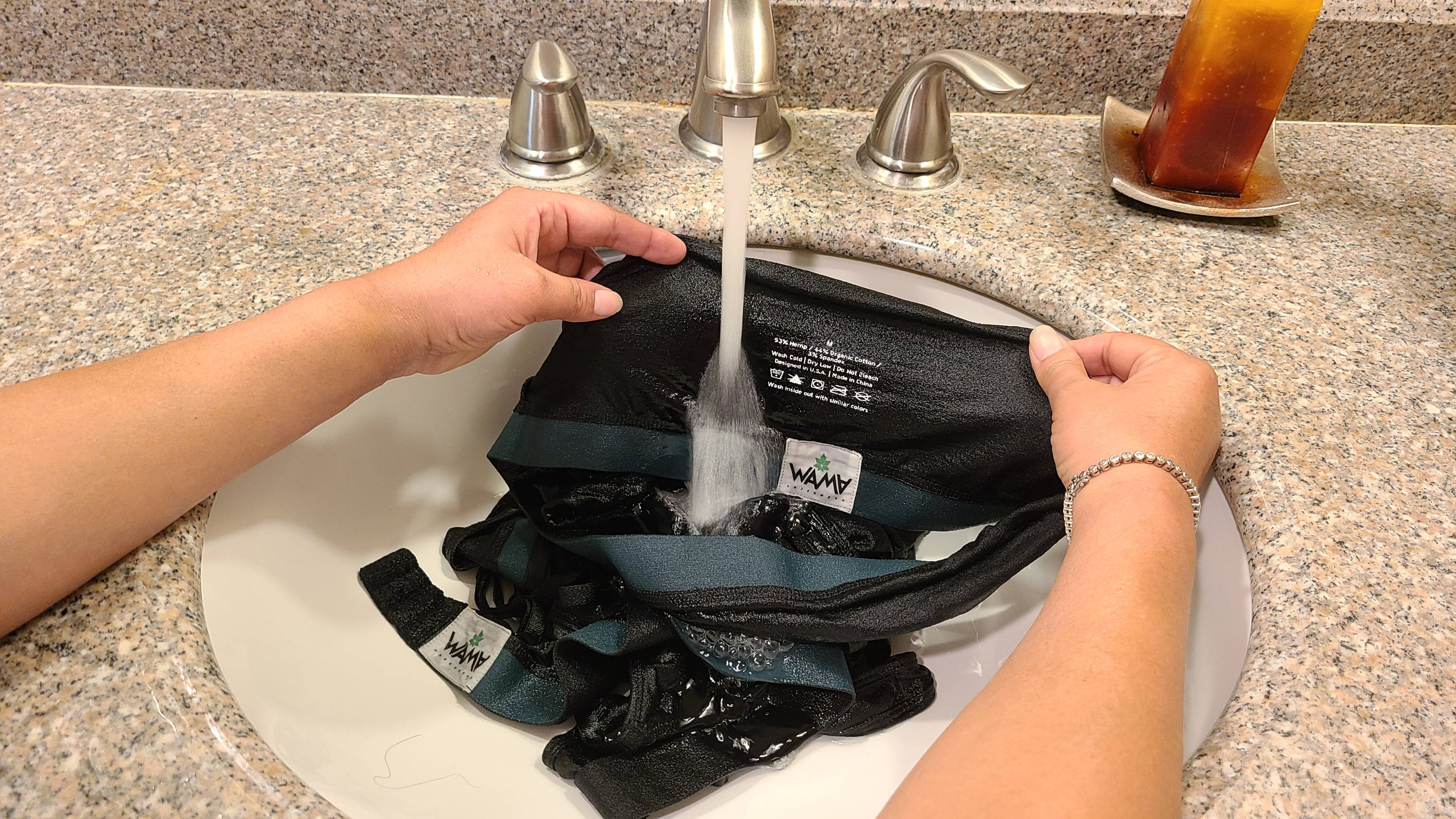 Woman hand washing WAMA Underwear Bras in a sink