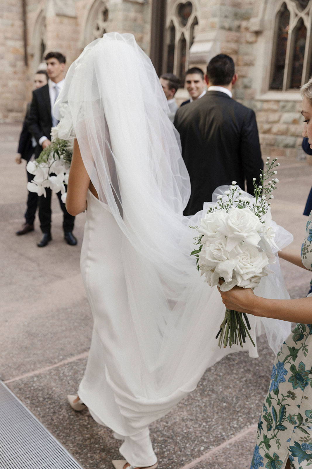 La demoiselle d'honneur tient le voile de la mariée.