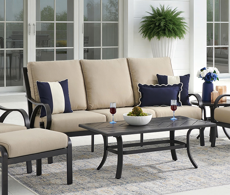 Outdoor seating area with beige cushions, dark furniture, and decorative pillows.