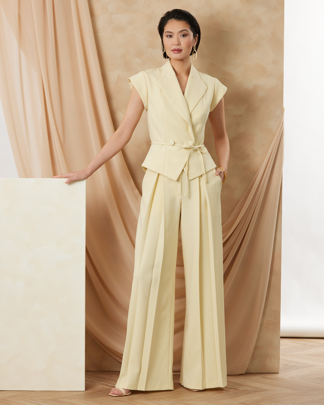 Woman in a yellow outfit poses against a soft, neutral backdrop.