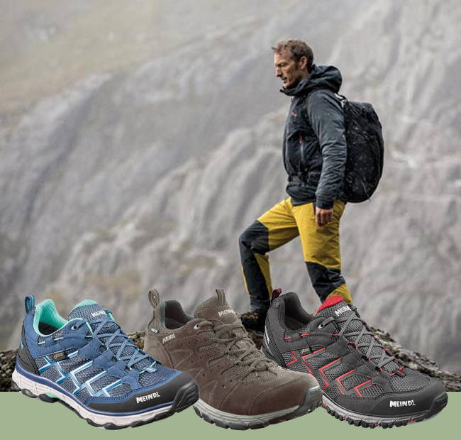 Man standing on mountain with range of Meindl Walking Shoes.