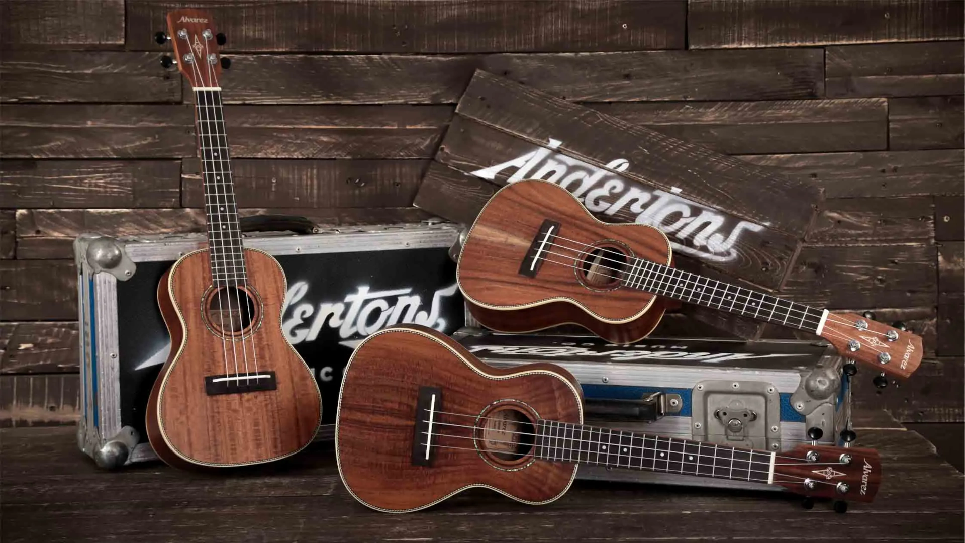 Three ukuleles on a wooden background with Andertons branding.