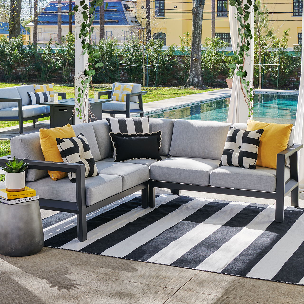 Outdoor seating area with gray sectional sofa and striped rug.