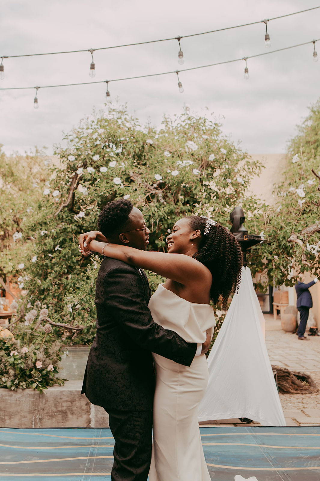 Bride and groom laughing together in front of floral tree